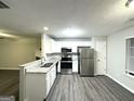 Modern kitchen featuring stainless steel appliances, white cabinets, and durable gray laminate flooring at 408 Kendall Ln, Mcdonough, GA 30253