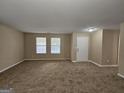 Bright living room with two windows, neutral walls, and new carpeting near front entry at 1110 Saint Phillips Ct, Locust Grove, GA 30248