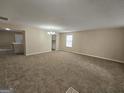 Spacious living room featuring neutral paint, plush carpeting, and a view of the kitchen at 1110 Saint Phillips Ct, Locust Grove, GA 30248