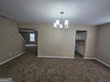 Open-concept living space with neutral walls, a modern chandelier, and views of the staircase at 1110 Saint Phillips Ct, Locust Grove, GA 30248