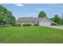Charming single-story home featuring a manicured lawn, trimmed hedges, and a two-car garage at 130 Belmont Trl, Covington, GA 30016