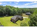 An aerial view showcasing a brick home on a sprawling lot with mature trees and a swimming pool in the distance at 3950 Chattahoochee Rd, Cumming, GA 30041