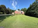 Beautiful brick home with a well-manicured lawn, lush greenery, and a detached garage under a bright, partly cloudy sky at 4119 Alayna Lee Cir, Mcdonough, GA 30252