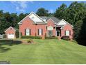 Charming brick home with a well-manicured lawn, lush greenery, and a detached garage on a sunny day at 4119 Alayna Lee Cir, Mcdonough, GA 30252