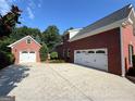 Spacious driveway leading to an attached two-car garage and a detached garage, surrounded by lush greenery at 4119 Alayna Lee Cir, Mcdonough, GA 30252