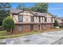 An exterior view of a brick Tudor-style townhome with mature landscaping at 3232 Abbeywood Dr, Decatur, GA 30034