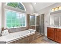 Bright bathroom featuring a soaking tub, glass-enclosed shower, and a large window at 44 Willow Leaf Way, Sharpsburg, GA 30277