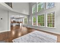Bright living room showcasing soaring ceilings, large windows with verdant views, and hardwood floors at 44 Willow Leaf Way, Sharpsburg, GA 30277