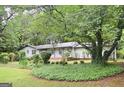 Single-story home with lush landscaping, mature trees, and a well-manicured lawn at 1590 Colonial South Sw Dr, Conyers, GA 30094