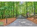 Gated entrance surrounded by lush trees and landscaping for added privacy at 305 Postwood Dr, Fayetteville, GA 30215