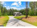Two-story home featuring lush green lawn, a long driveway and wooded backyard at 74 Riverwood Trl, Grantville, GA 30220