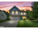 Charming two-story home featuring a well-manicured lawn and a mix of brick and siding accents at sunset at 149 Pristine Dr, Locust Grove, GA 30248
