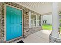 View of the inviting front porch with a vibrant teal door and brick accents at 149 Pristine Dr, Locust Grove, GA 30248