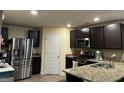Modern kitchen featuring stainless steel appliances, granite countertops, and dark wood cabinetry at 175 Bridgemill Dr, Covington, GA 30014