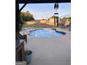 Backyard pool with a concrete surround, featuring a wind chime, lounge chairs, and wooden fence at 175 Bridgemill Dr, Covington, GA 30014
