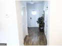 Bright hallway featuring hardwood floors and leading to a white front door with glass panels at 2845 Long Shadow Ct, Snellville, GA 30078