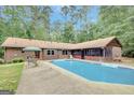 Inviting backyard with a sparkling blue pool, patio area, and lush greenery at 9706 Holly Hill Way, Jonesboro, GA 30238