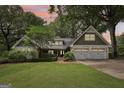 Charming home with white painted stone, shake accents, manicured lawn, and a two-car garage at dusk at 3612 Bill Gardner Pkwy, Locust Grove, GA 30248