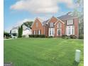 Expansive front lawn leads to a stately brick home with black shutters and lush greenery, creating an inviting exterior at 12043 Olmstead Dr, Fayetteville, GA 30215