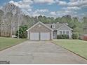 Inviting single-Gathering home featuring a two-car garage, stone accents, manicured lawn and mature trees at 131 Meadowbrook Ln, Grantville, GA 30220