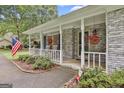 Inviting front porch with classic white columns, red hanging baskets and brick accents, showcasing southern charm at 107 Jennings Yard, Peachtree City, GA 30269