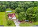 Aerial view of the property featuring a home with a pool, playground, vehicles, and surrounding trees at 161 Mills Dr, Covington, GA 30016