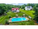 Aerial view of backyard with an in-ground pool, patio with umbrellas and a playground surrounded by trees at 161 Mills Dr, Covington, GA 30016