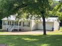 Single-story home with metal roof, covered porch, attached garage, and driveway surrounded by trees and grass at 5761 Hancock Dr, Social Circle, GA 30025