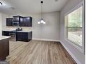 Contemporary kitchen with dark cabinets, stainless steel appliances, and durable vinyl flooring, illuminated by natural light at 473 Cherry Creek Dr, Loganville, GA 30052