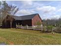 Exterior shot of a single story red brick home with white picket fence in yard at 390 Burg Rd, Locust Grove, GA 30248