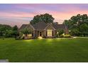 Inviting brick home with lush green lawn and mature trees at dusk at 10 Wigwam Cir, Whitesburg, GA 30185