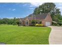 Expansive lawn leads to a brick home with attached garage and covered parking at 10 Wigwam Cir, Whitesburg, GA 30185