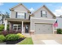 Attractive two-story home with gray siding, brick accents, a two-car garage, covered porch and American flag at 372 Cobblestone Trl, Dallas, GA 30157