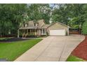 View of a lovely two-story home with a two-car garage and a long driveway with mature trees at 4080 Derby Dr, Cumming, GA 30040