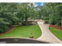 Aerial view of a landscaped two-story home with an extended driveway and a large front yard surrounded by mature trees at 4080 Derby Dr, Cumming, GA 30040