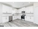 Modern kitchen featuring stainless steel appliances, granite countertops, white cabinets, and gray wood-look flooring at 3392 Arabian Farm Ln, Dacula, GA 30019