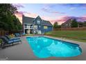 Backyard oasis featuring a sparkling pool, lounge chairs, and a covered patio perfect for entertaining at 150 Surrey Chase Dr, Social Circle, GA 30025