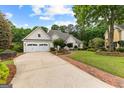 Charming home with manicured front yard, brick path, and long driveway to 3-car garage at 134 Mellington Ln, Peachtree City, GA 30269