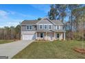 Charming two-story home boasts a landscaped yard, attached two-car garage, and traditional architectural details at 221 Ruthe Cv, Locust Grove, GA 30248