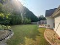 Backyard showcasing a spacious lawn, privacy fence, bordered by decorative rock and a swing set at 240 Turnbridge Cir, Peachtree City, GA 30269