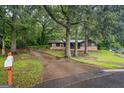 Exterior shot of home, featuring a long driveway leading up to a stone and wood-clad house surrounded by trees at 69 Trace Ct, Stockbridge, GA 30281