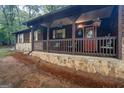 Close-up of the front porch with rocking chairs, decorative hanging plants, and stone accents on a wood-clad home at 69 Trace Ct, Stockbridge, GA 30281