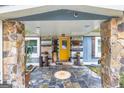 Inviting covered entryway featuring stone pillars, tile flooring, and a striking yellow front door at 7138 Rockland Rd, Lithonia, GA 30038