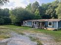 Inviting home with a gravel driveway and a well-maintained lawn, surrounded by lush greenery at 7138 Rockland Rd, Lithonia, GA 30038