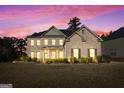 Charming two-story brick home with a manicured lawn and a covered front porch during a beautiful sunset at 6857 Louis Dr, Locust Grove, GA 30248