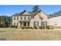 Beautiful two-story brick home featuring a well-maintained lawn, mature landscaping, and classic architectural details at 6857 Louis Dr, Locust Grove, GA 30248