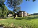 Spacious backyard of a brick home featuring a lush green lawn, chain link fence and mature trees at 624 Kristen Ct, Mcdonough, GA 30252