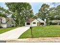 A charming white bungalow with lush landscaping, mature trees, and a well-maintained lawn at 203 First Leaf, Peachtree City, GA 30269