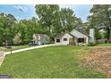A charming white bungalow with lush landscaping, mature trees, and a well-maintained lawn at 203 First Leaf, Peachtree City, GA 30269