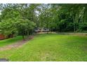 Lush green lawn leading up to a charming home surrounded by mature trees and landscaping at 243 Howell Sw Ter, Atlanta, GA 30331